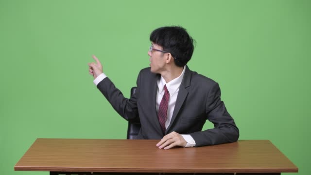 Junge-asiatische-Geschäftsmann-als-Nachrichtensprecher-reden-und-präsentieren-etwas-auf-der-Rückseite