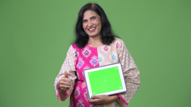 Reife-gerne-schöne-Inderin-zeigt-digital-Tablette-und-Daumen-aufgeben
