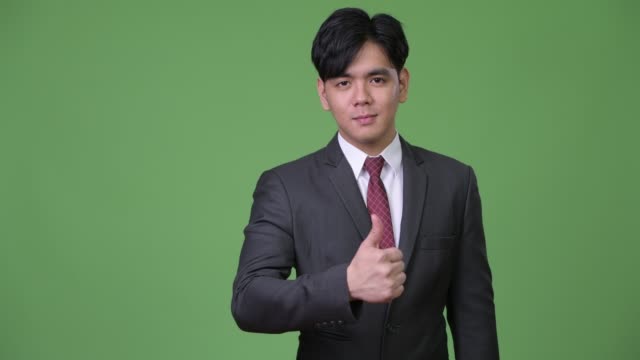 Young-handsome-Asian-businessman-giving-thumbs-up