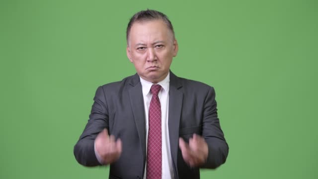 Reife-japanischer-Geschäftsmann-zeigt-Mittelfinger