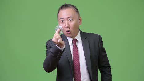 Mature-Japanese-businessman-playing-with-fidget-spinner