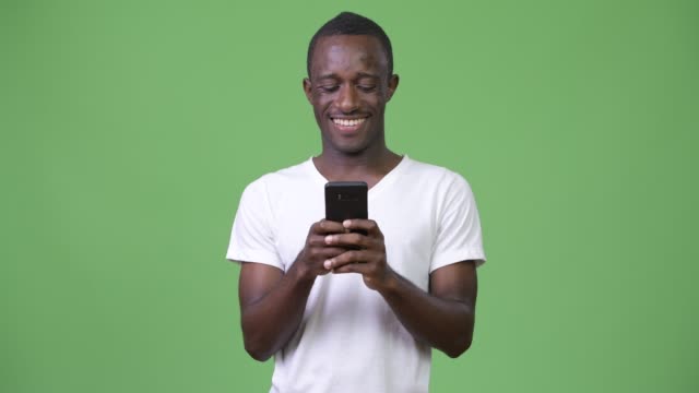 Junge-afrikanische-Mann-mit-Handy-vor-grünem-Hintergrund