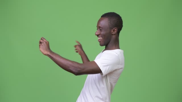 Young-African-man-video-calling-with-phone-against-green-background