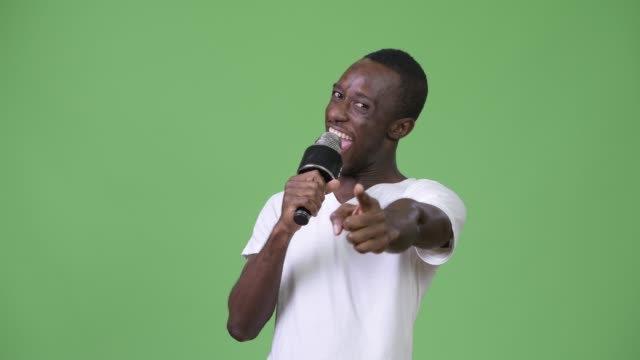 Young-happy-African-man-smiling-while-speaking-on-microphone