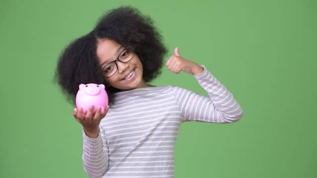 Young-cute-African-girl-with-Afro-hair-holding-piggy-bank-and-giving-thumbs-up