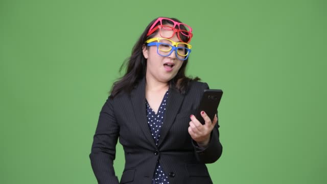 Madura-empresaria-asiática-hermosa-usar-el-teléfono-mientras-usa-muchos-lentes-como-concepto-divertido
