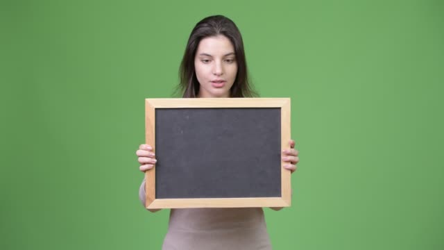 Young-beautiful-woman-looking-shocked-while-holding-blackboard