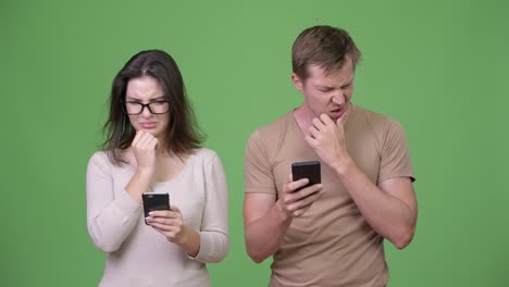 Young-couple-thinking-while-using-phone-together