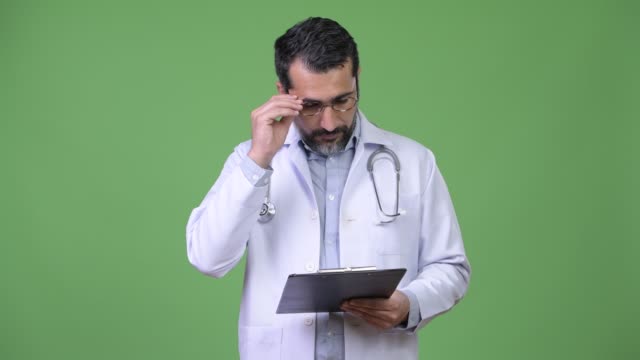 Handsome-Persian-bearded-man-doctor-reading-clipboard