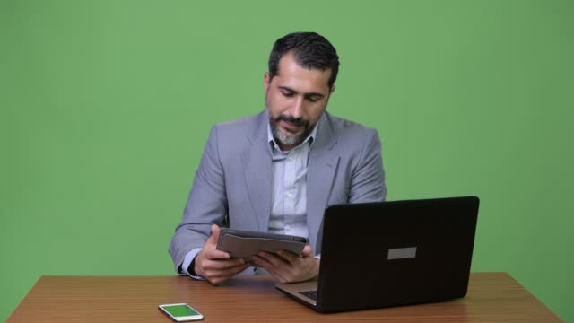 Betonte-persische-bärtigen-Geschäftsmann-Multitasking-bei-der-Arbeit-und-auf-der-Suche-beschäftigt
