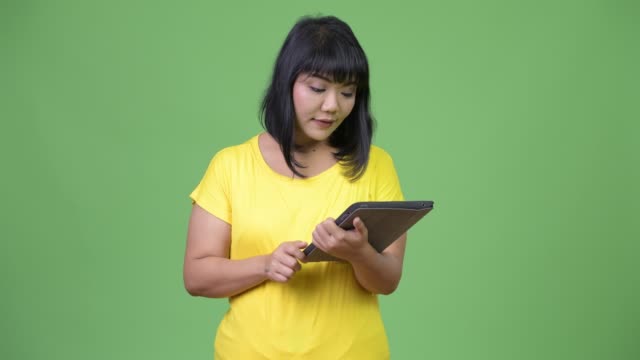 Schöne-asiatische-Frau-denken-bei-der-Verwendung-von-digital-Tablette