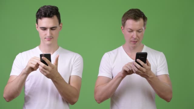 Two-happy-young-handsome-men-using-phones-together