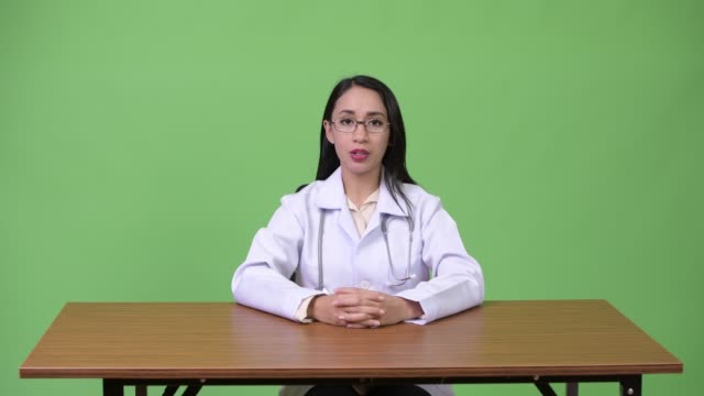 Junge-schöne-asiatische-Frau-Arzt-im-Gespräch-mit-Kamera