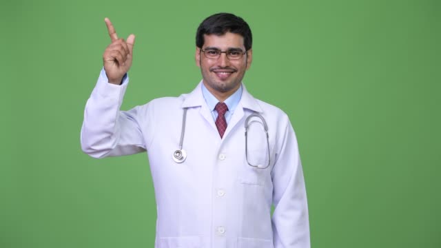 Young-handsome-Persian-man-doctor-pointing-up