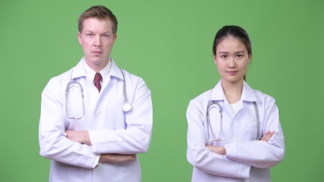 Multi-ethnic-couple-doctors-with-arms-crossed-together