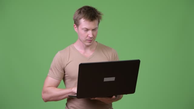 Young-happy-Scandinavian-man-thinking-while-using-laptop