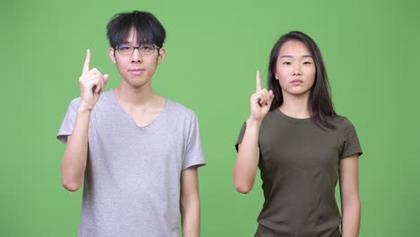 Young-Asian-couple-pointing-up
