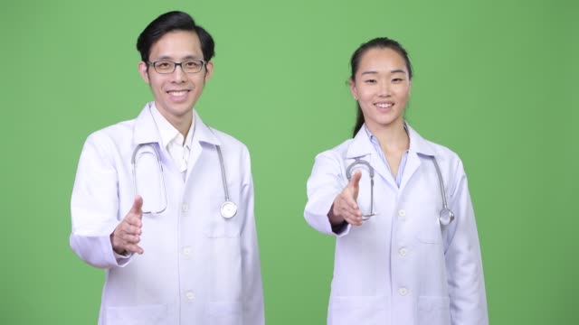 Young-Asian-couple-doctors-giving-handshake-together