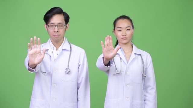 Médicos-de-la-joven-pareja-asiática-con-gesto-de-parada-junto