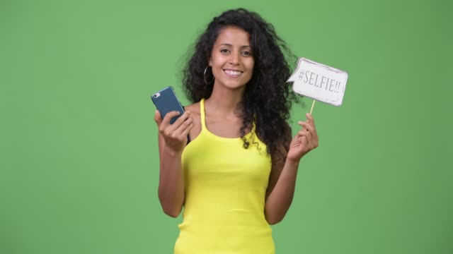 Junge-schöne-Hispanic-Frau-mit-Telefon-und-Selfie-Papier-Schild