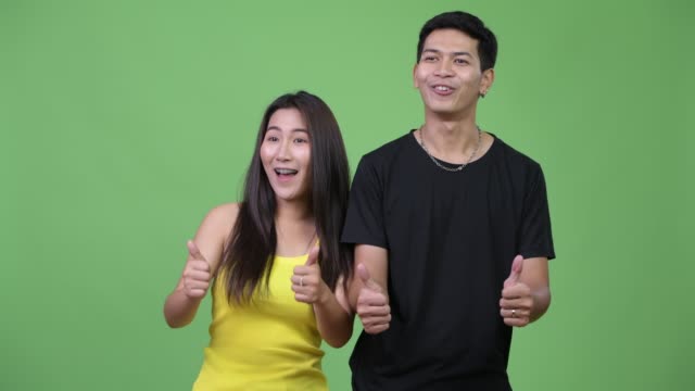 Jóvenes-asiáticos-par-dar-pulgares-para-arriba-juntos