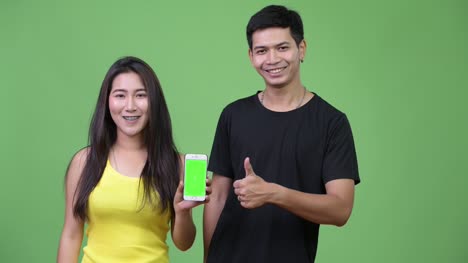 Junge-asiatische-Paar-zeigt-Handy-zusammen