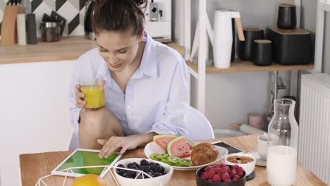 Mujer-joven-con-una-tableta-durante-el-desayuno