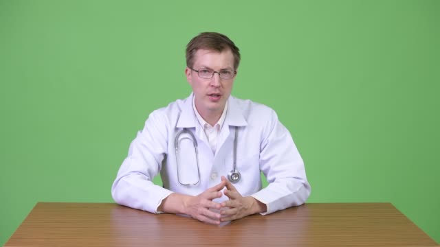 Young-Confident-Man-Doctor-Sitting-And-Talking-While-Gesturing