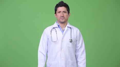 Hispanic-Mann-Arzt-vor-grünem-Hintergrund