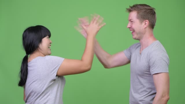 Young-multi-ethnic-couple-giving-high-five-and-crossing-arms-together