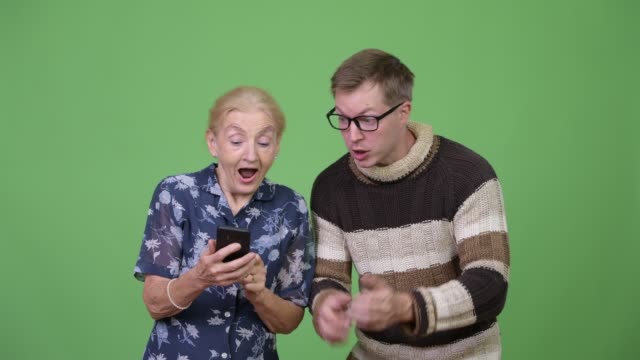 Glückliche-Großmutter-und-Enkel-mit-Telefon-dann-Daumen-zusammen-aufgeben