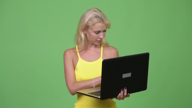 Joven-mujer-rubia-hermosa-feliz-usando-laptop-sobre-fondo-verde