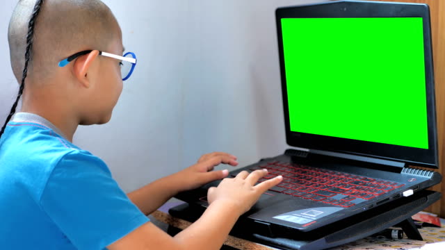 Los-asiáticos-niño-jugando-ordenador-portátil-y-pantalla-verde.-Feliz-disfrutar-niños-ordenador-en-casa.