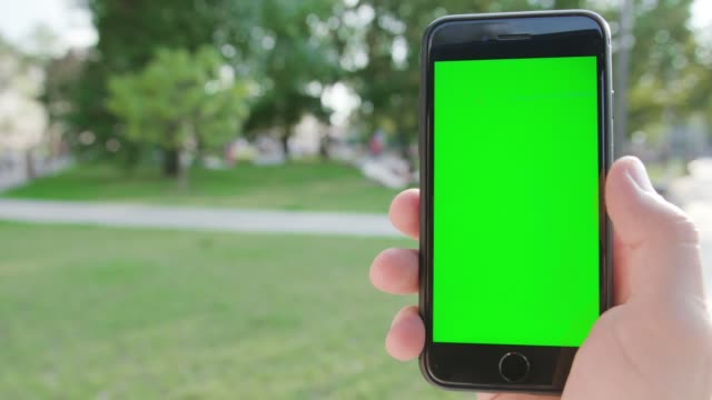 A-Hand-Holding-a-Phone-with-a-Green-Screen