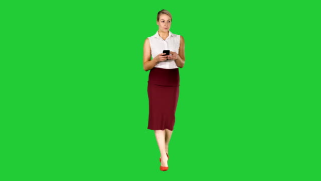 Woman-typing-write-message-on-smart-phone-and-walking-on-a-Green-Screen,-Chroma-Key