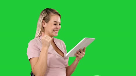 Woman-sitting-watching-tablet-pc-and-smiling-on-a-Green-Screen,-Chroma-Key