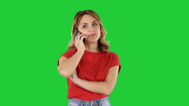 Junge-schöne-Frau-im-roten-T-shirt-spricht-über-Handy-auf-einem-Green-Screen,-Chroma-Key