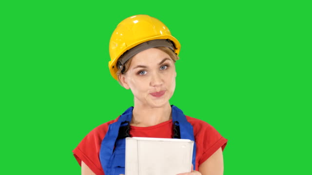 Young-construction-worker-with-tablet-computer-presenting-something-on-a-Green-Screen,-Chroma-Key