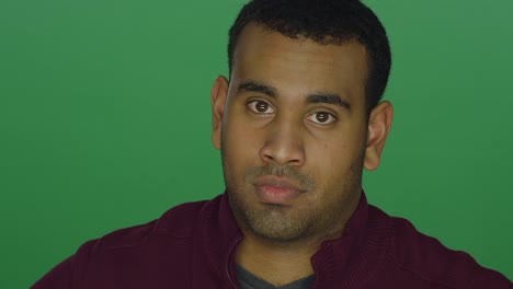 Young-African-American-man-staring-disapprovingly-and-shaking-his-head,-on-a-green-screen-studio-background