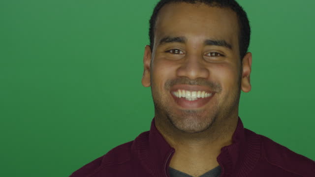 Young-African-American-man-smiling-and-nodding-his-head,-on-a-green-screen-studio-background