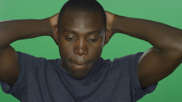 Young-African-American-man-looks-sad-and-upset,-on-a-green-screen-studio-background