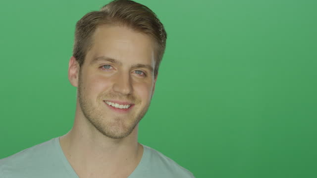 Junger-Mann-lächelt-charmant,-auf-einem-green-Screen-Studio-Hintergrund