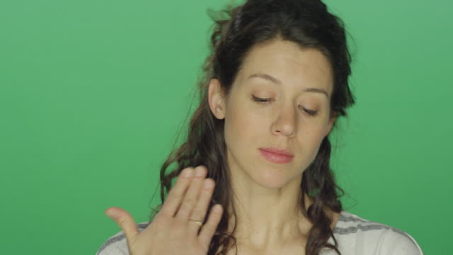 Young-woman-starting-to-feel-better-after-crying,-on-a-green-screen-studio-background