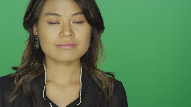 Mujer-asiática-joven-mirando-triste,-sobre-un-fondo-de-estudio-de-pantalla-verde