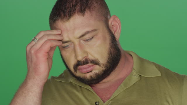 Muscular-man-looking-concerned,-on-a-green-screen-studio-background