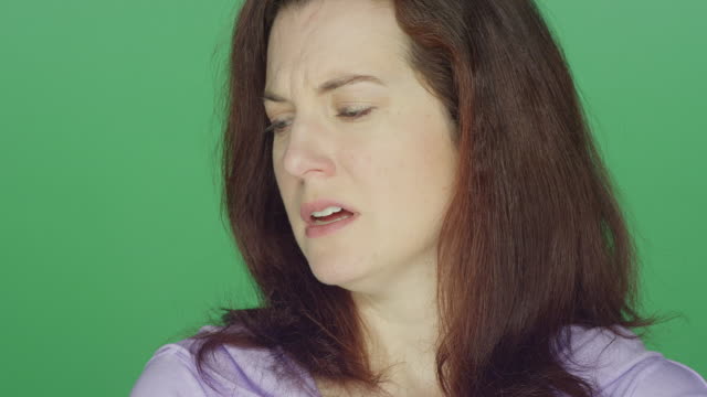 Young-redhead-woman-looking-sad,-on-a-green-screen-studio-background