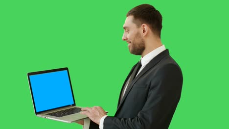 Mittlere-Schuss-eines-schönen-Geschäftsmann-hält-Laptop-funktioniert-mit-einem-Touchpad.-Wir-sehen-blau-Notebookbildschirm,-alle-erschossen-auf-einem-Green-Screen-Hintergrund.