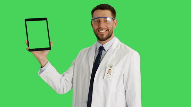 Tiro-medio-de-un-científico-guapo-vistiendo-gafas-protectoras-sosteniendo-una-tableta-con-una-mano-y-haciendo-deslizar-gestos-tocando-con-otro.-La-tableta-y-el-fondo-son-pantalla-verde.