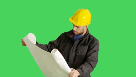 Mittelschuss-eines-Arbeiters,-der-harte-Hut-und-Pläne-und-Blueprints-trägt.-Hintergrund-ist-Green-Screen.
