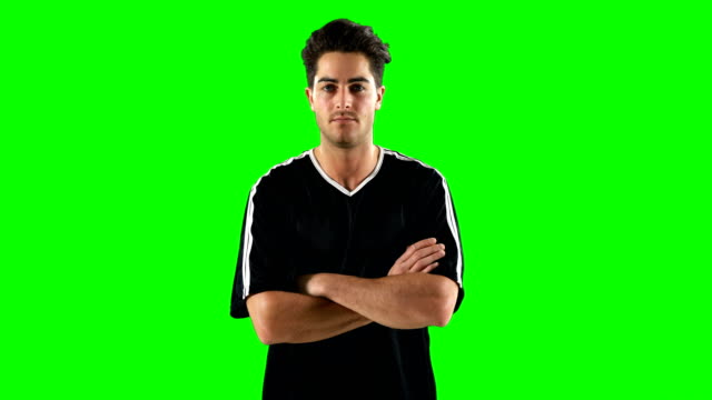 Confident-football-player-standing-against-green-screen